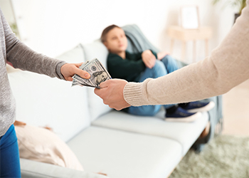 Man handing cash to a woman with a child in the background